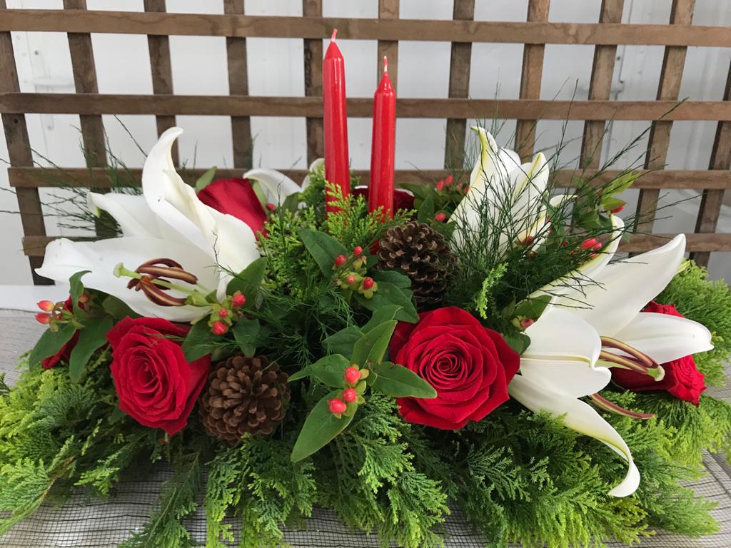 Arranjo floral natalino com velas, rosas vermelhas e lírios brancos