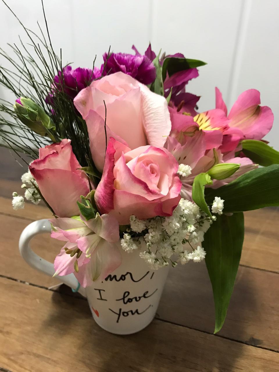 Arranjo floral com rosas cor de rosa em uma caneca love